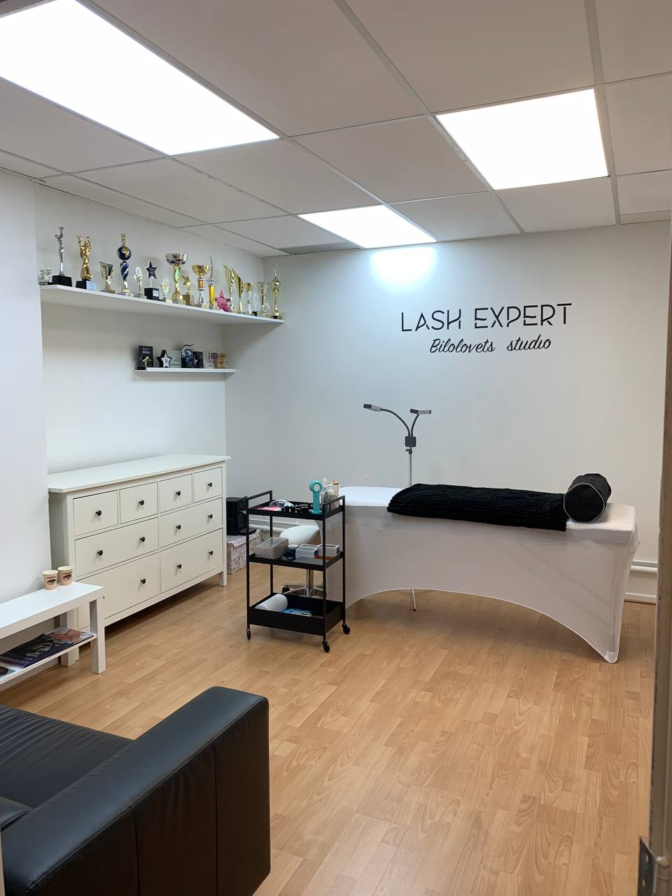 De studio gezien vanuit de deur: behandelbank, ladekast en de letters LASH EXPERT op de muur