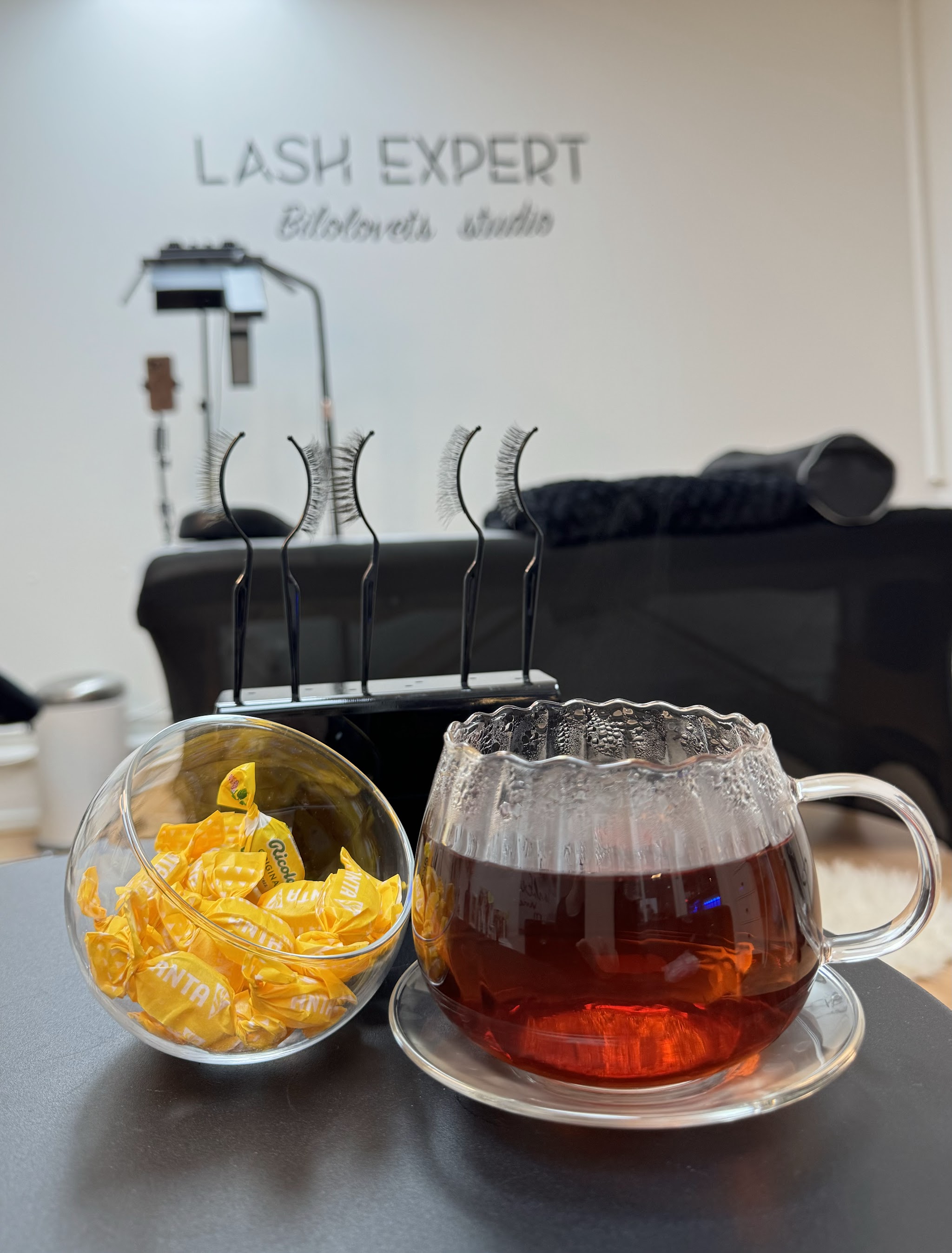 Een kop thee en een glazen pot met snoepjes op de tafel in de studio, de wandletters op de achtergrond
