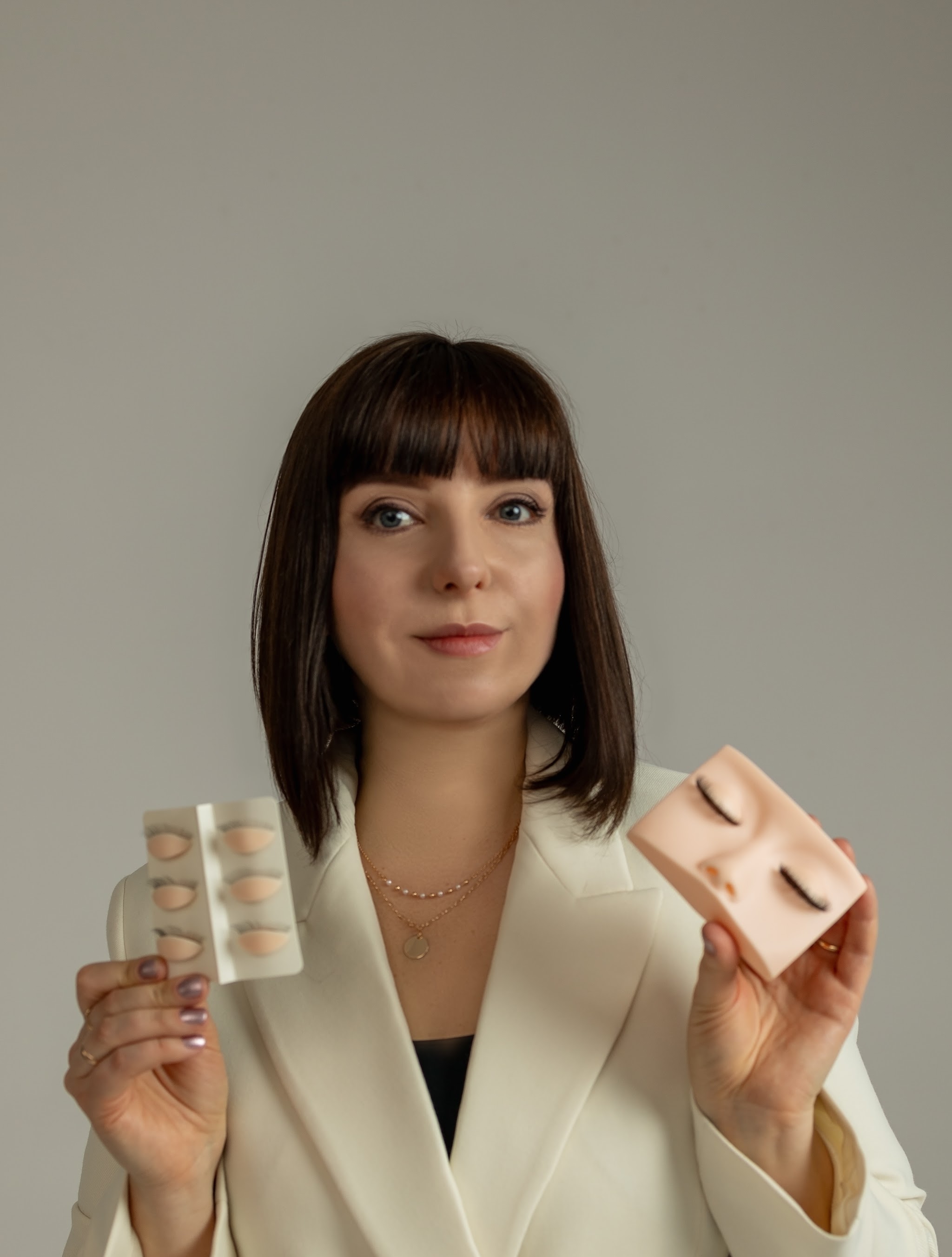 Tatiana Bilolovets in een witte blazer met twee oefenkaarten voor wimpers in haar handen